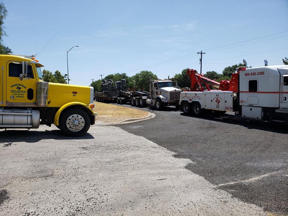 Welch Bros Towing yellow heavy-duty truck hauling a lowboy trailer with commercial equipment