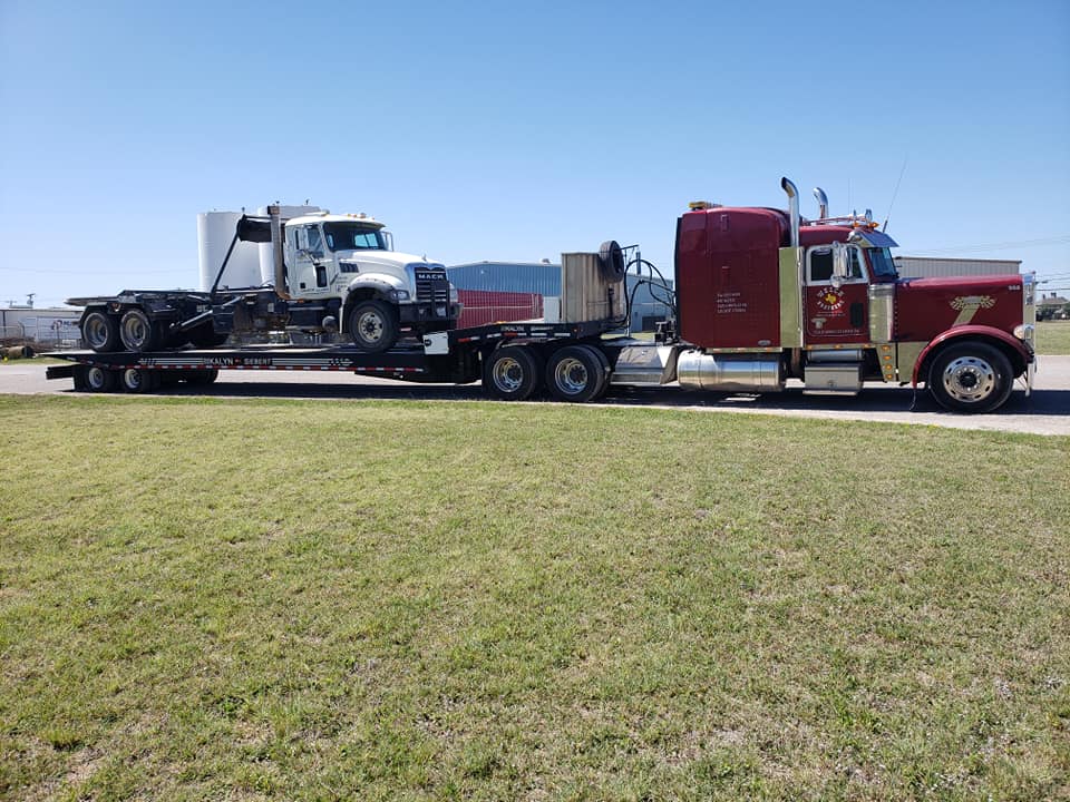 Welch Bros Towing red Peterbilt semi hauling a flatbed trailer with a Mack truck in Brownwood, TX
