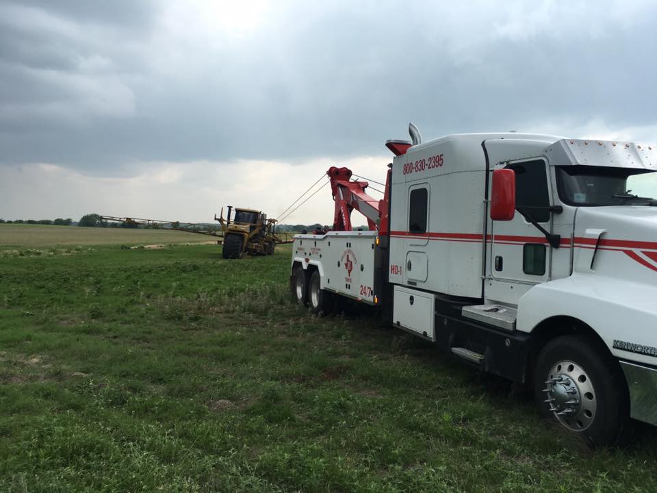 Heavy-duty tow truck recovering large farm equipment in a Central Texas field
