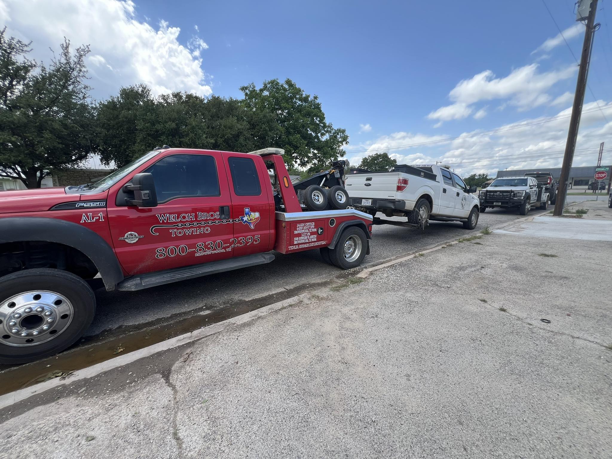 Welch Bros Towing wrecker towing a white pickup truck on a street in Brownwood, TX