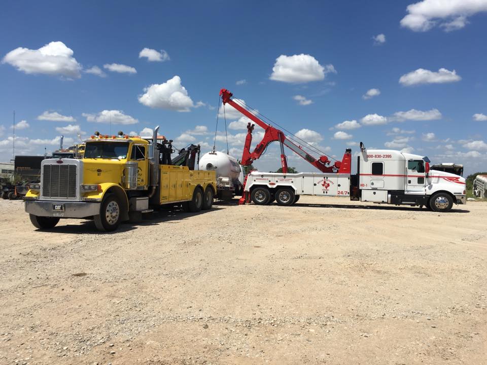 Heavy-duty wreckers using a crane winch to recover a propane tank trailer
